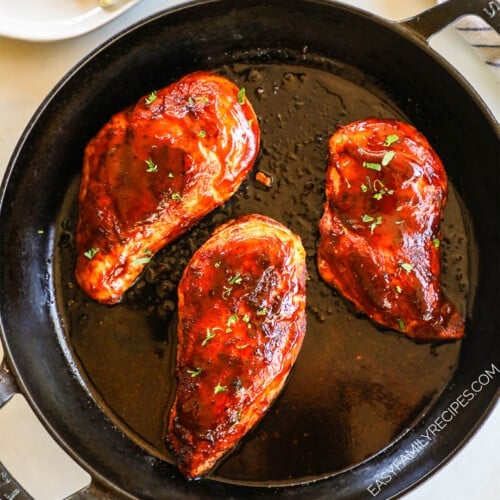 above image of three chicken breasts in a skillet covered with BBQ sauce.