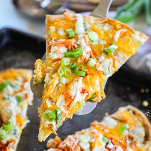 A piece of buffalo chicken flatbread being lifted out of the pan with a spatula.