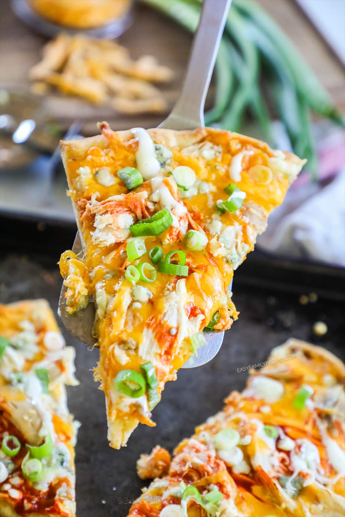 A piece of buffalo chicken flatbread being lifted out of the pan with a spatula.