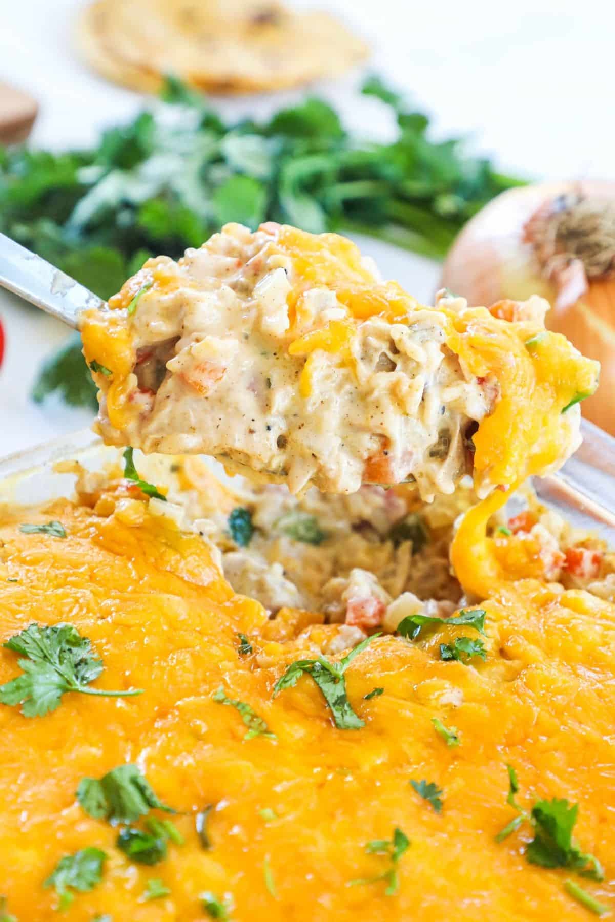 spoon lifting scoop of chicken fajita casserole out of baking dish