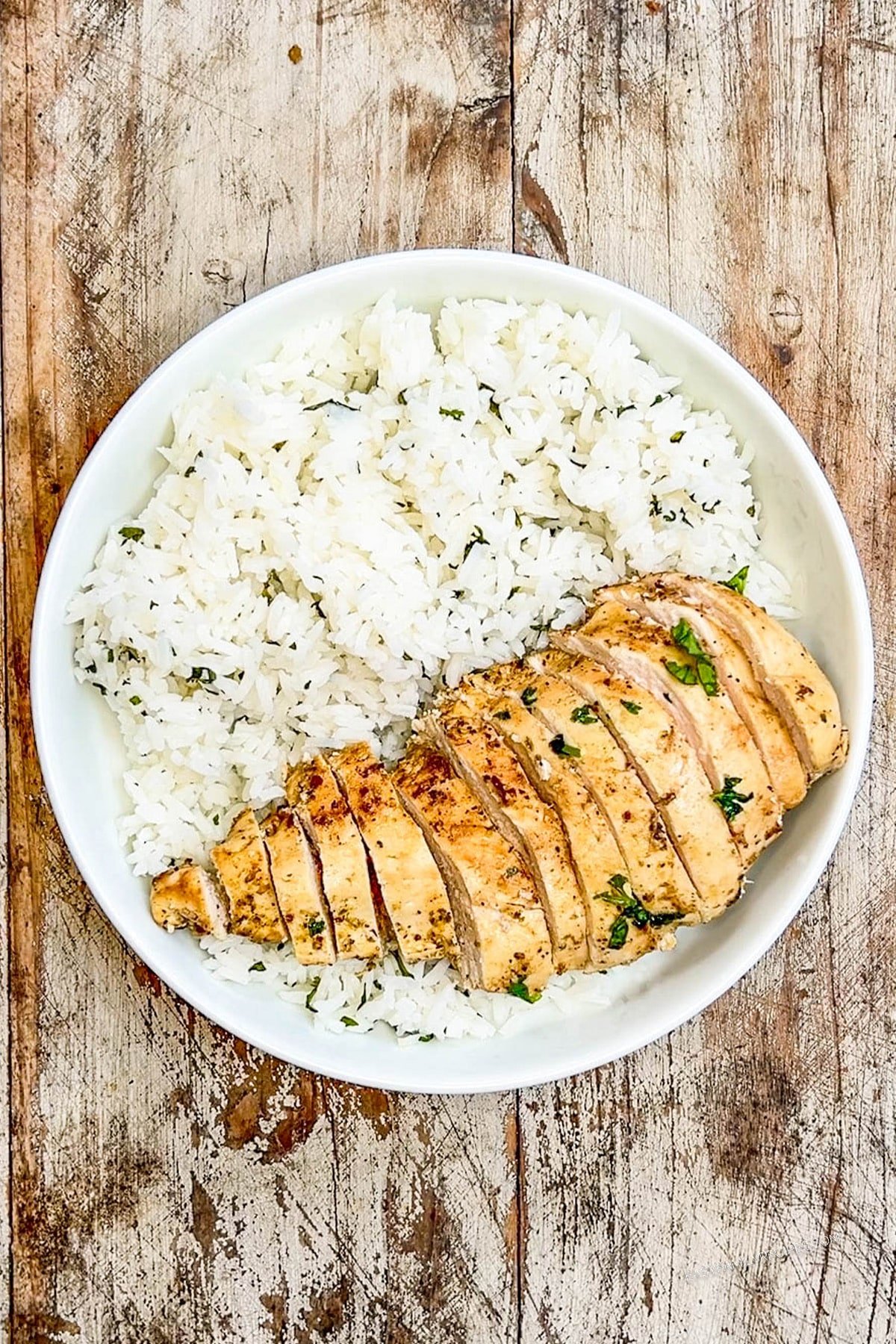 Cilantro lime rice and sliced baja chicken in a white bowl, the base for baja bowls.