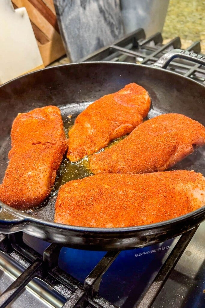 seasoned chicken breast being cooked in a skillet.