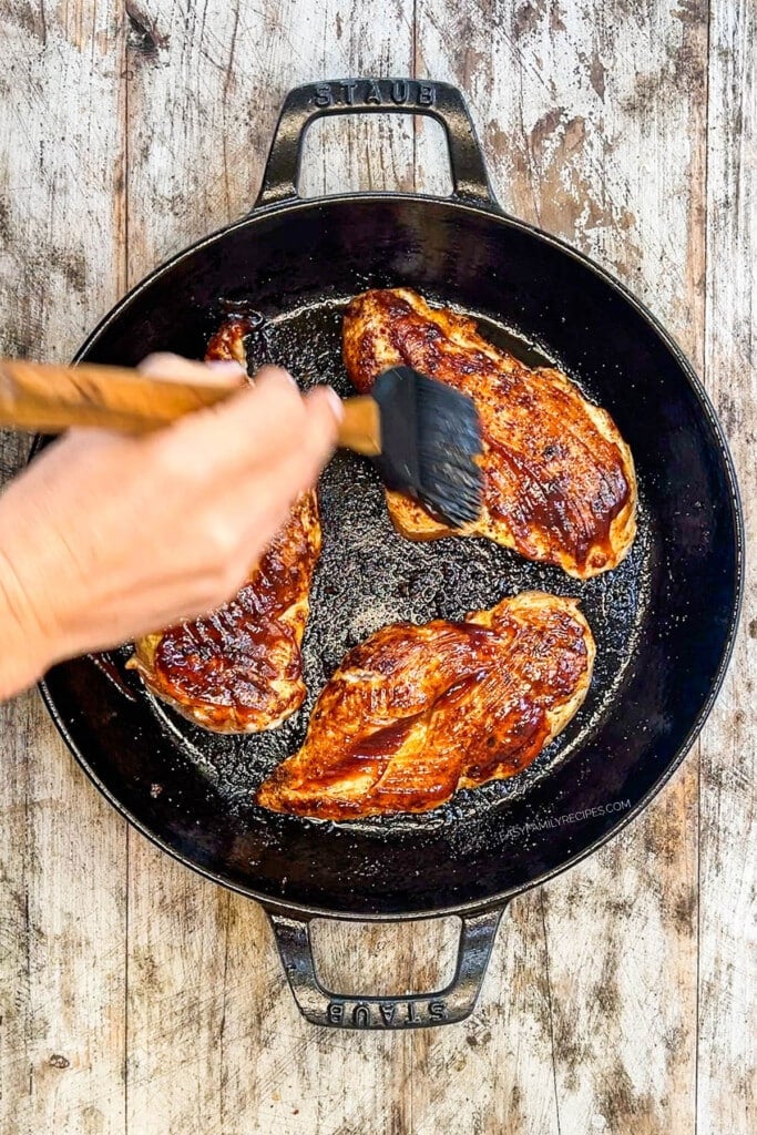 a spatula brushing the outside of the seared BBQ chicken