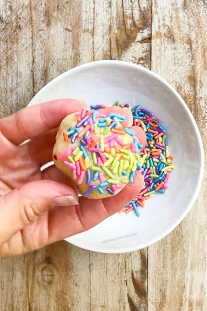 a cookie dough ball covered with sprinkles, held.