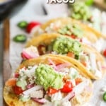 A row of Baja Chicken Tacos on a parchment-lined cutting board. The text reads, "Baja Chicken Tacos."