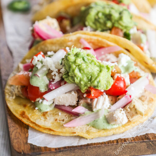 A row of Baja Chicken Tacos on a parchment-lined cutting board.