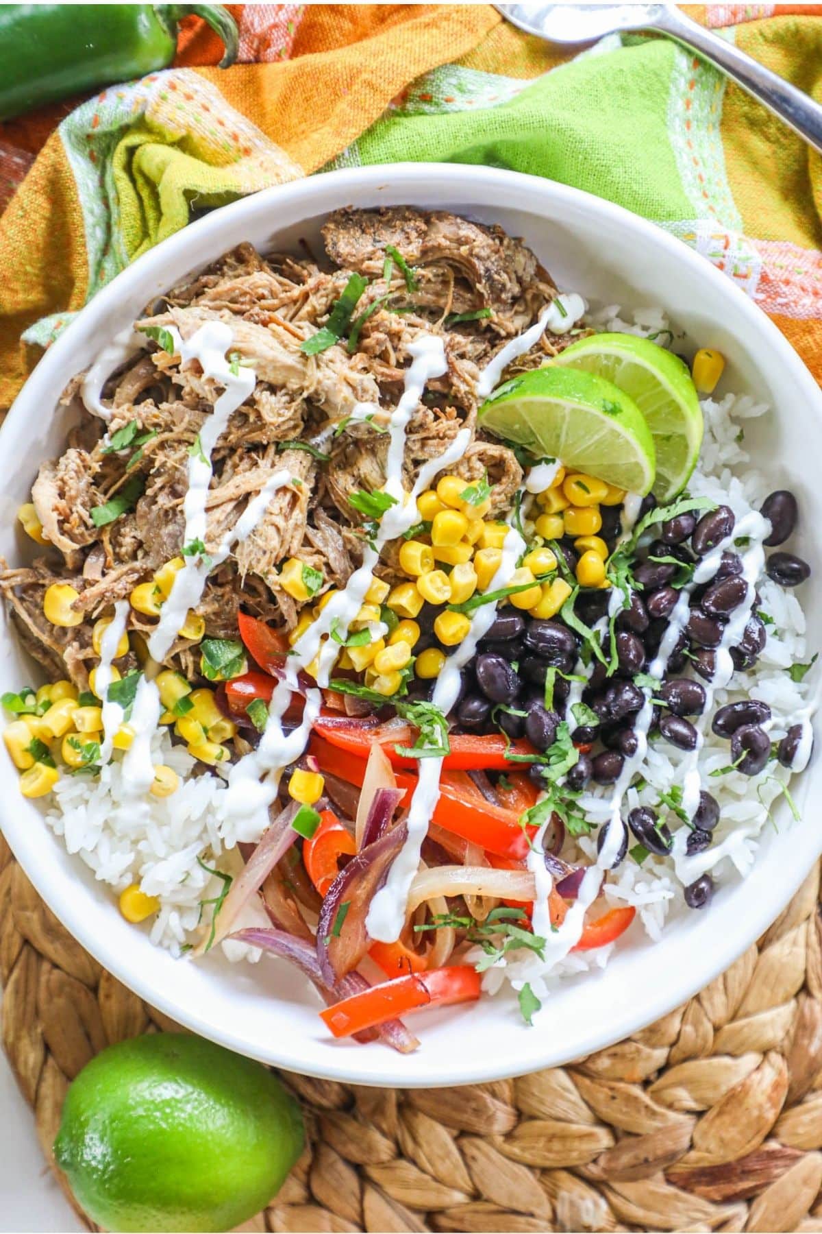 white bowl with pork carnitas, rice, black beans, corn limes, and red pepper