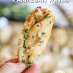 A hand holding a single slow cooker garlic Parmesan wing. The text reads, "Crock Pot Parmesan Wings."