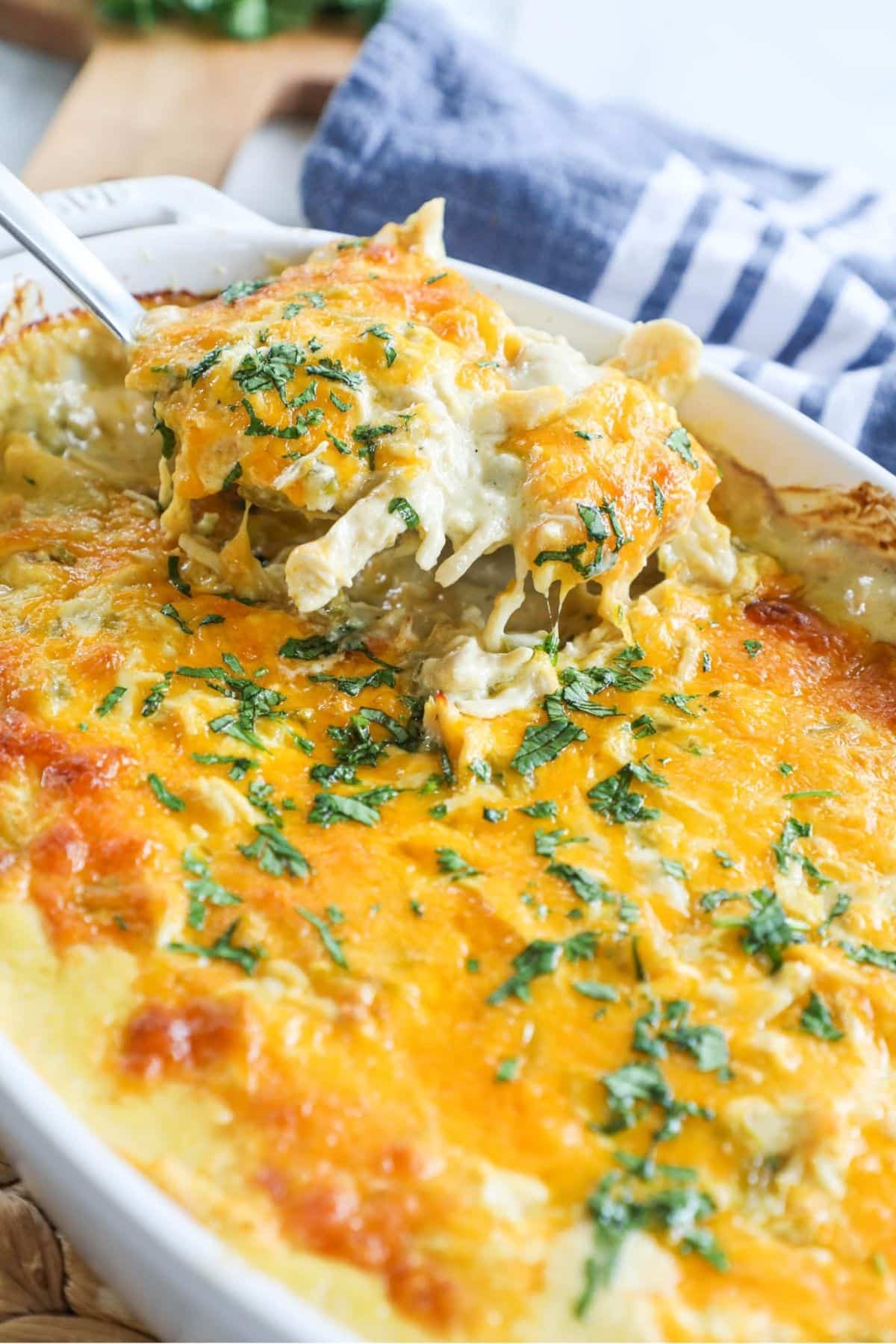 spoonful of green chile chicken casserole being scooped out of a white casserole dish