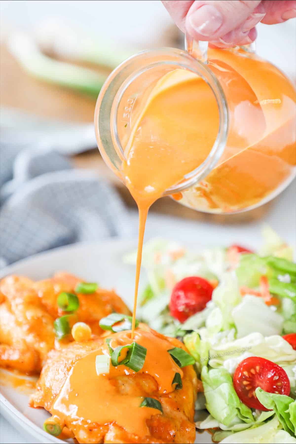 Pouring homemade buffalo sauce over chicken.