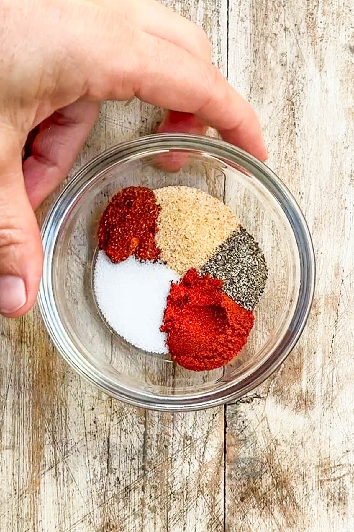 Seasonings for Asian Zing Wings in a small glass bowl with a distressed wood background.