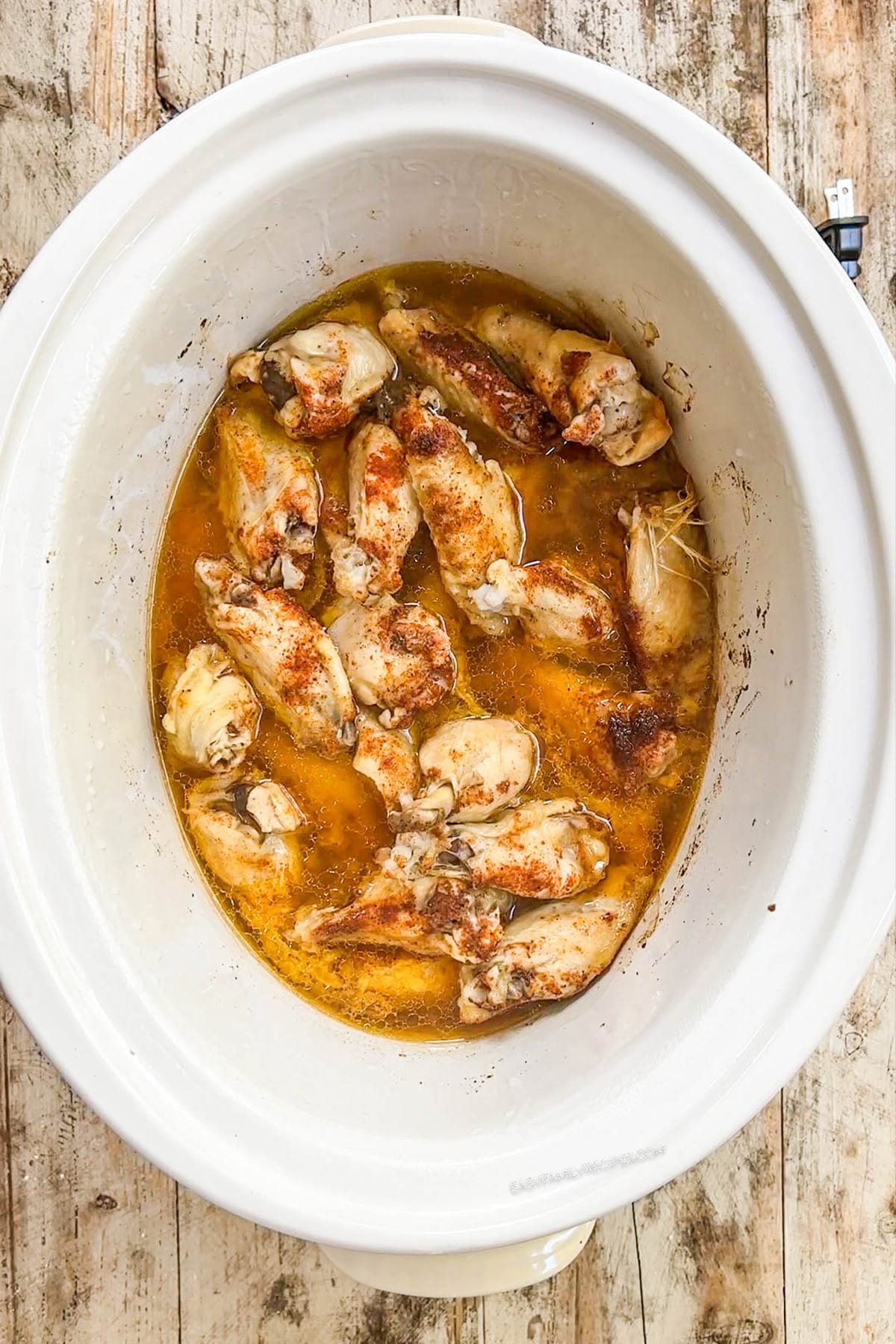 Asian Zing Wings being cooked in a white slow cooker.