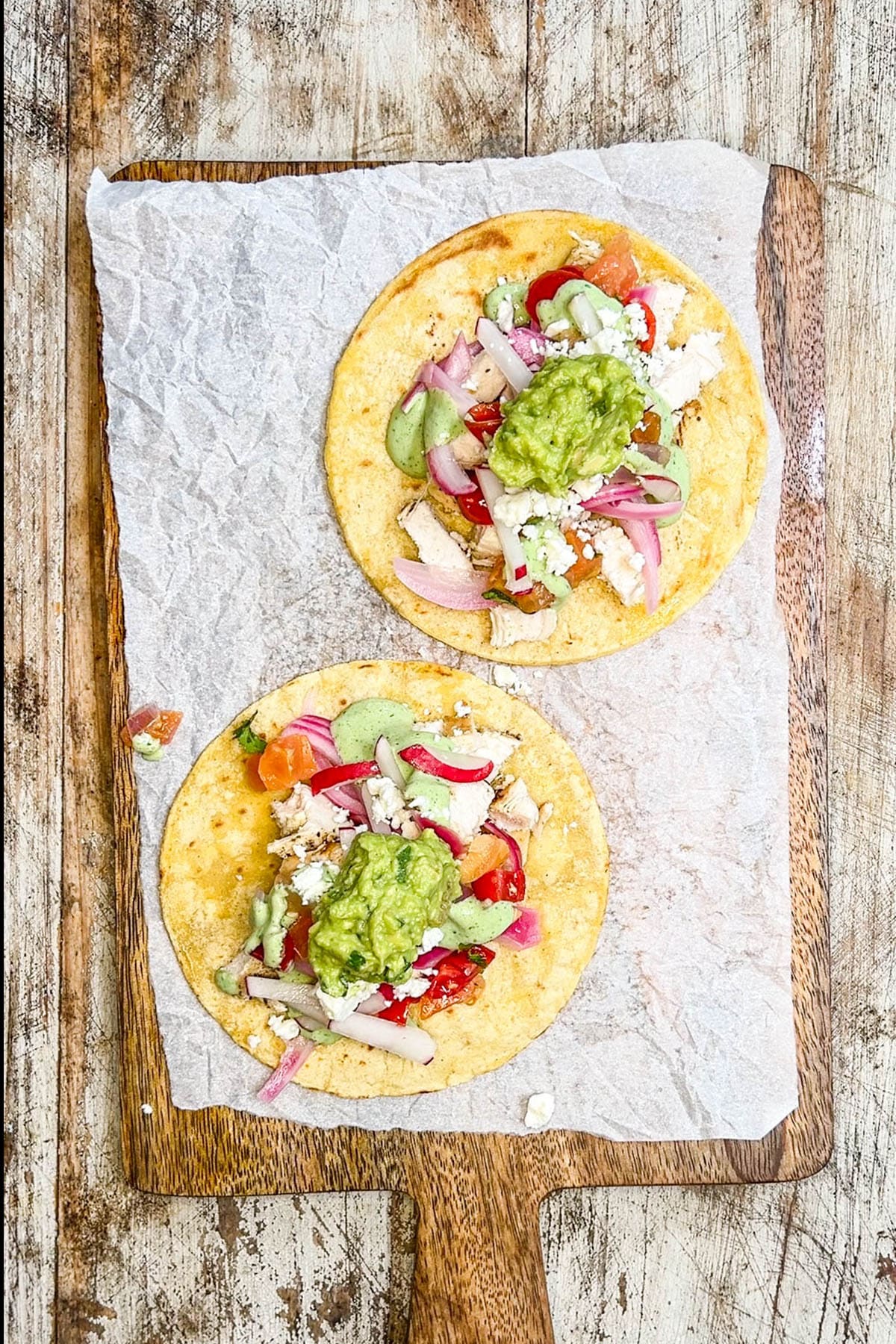 A top view of two tortillas being made into Baja Chicken Tacos. This is step 6 of the process, adding toppings.