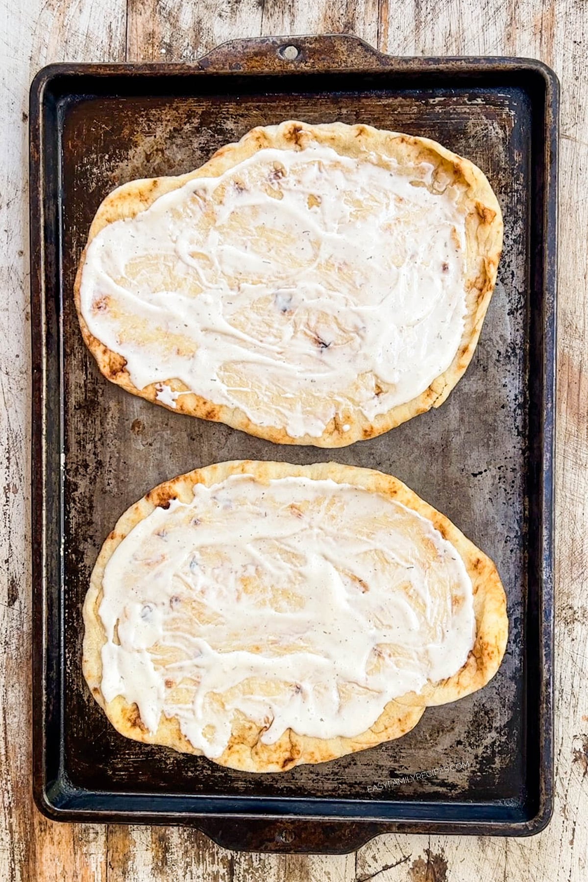 Spreading ranch onto naan flatbreads for chicken bacon ranch flatbread.