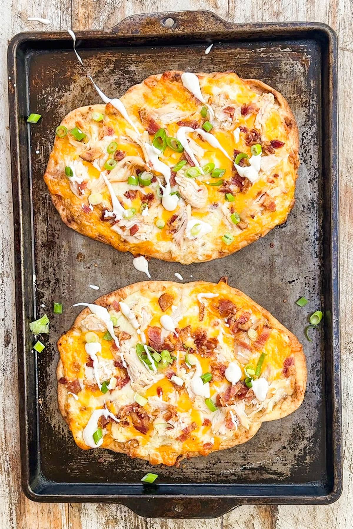 Two chicken bacon ranch flatbreads on a baking sheet.