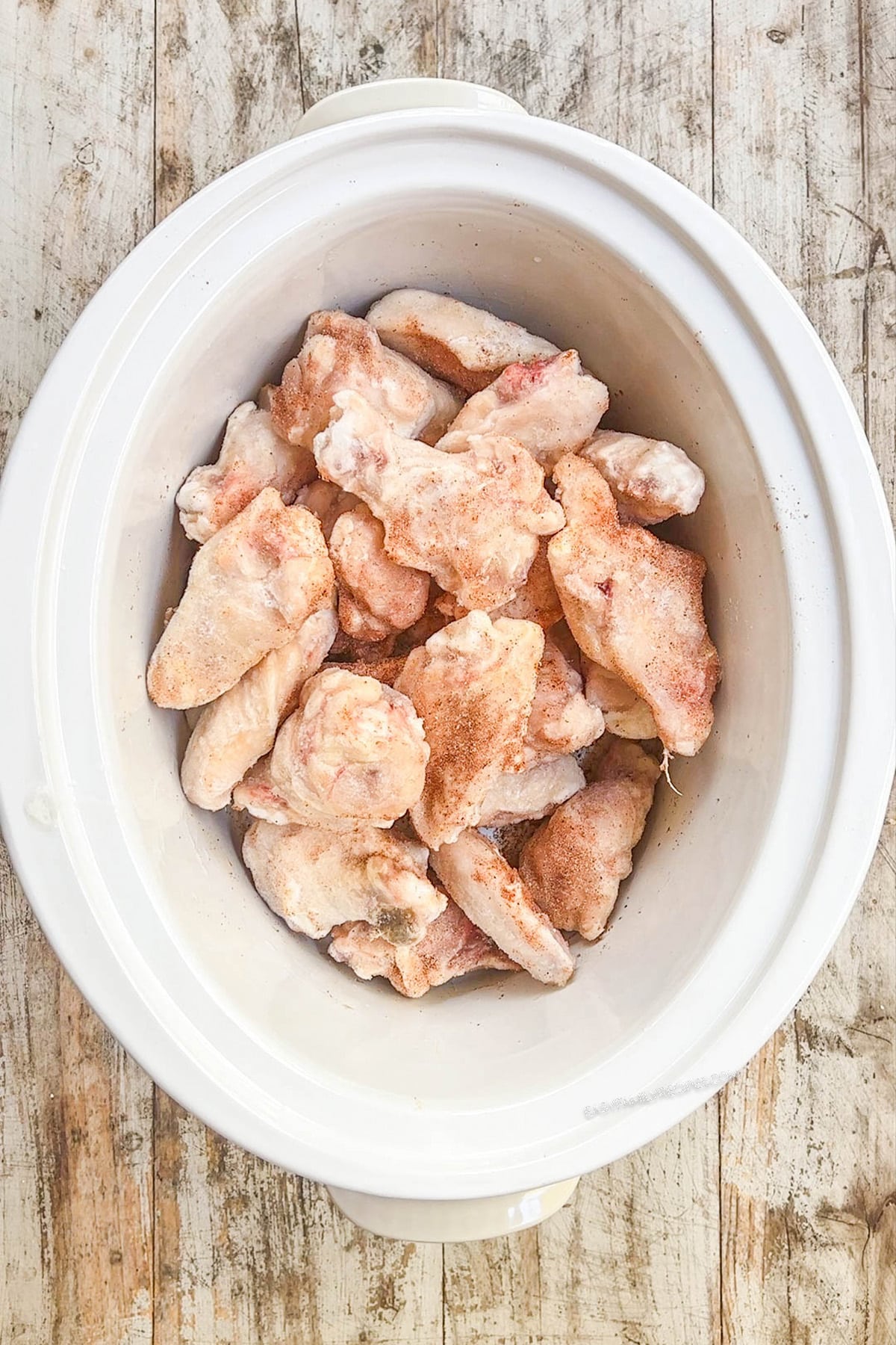 Wings for slow cooker garlic Parmesan wings are piled in the Crock Pot, ready to cook.