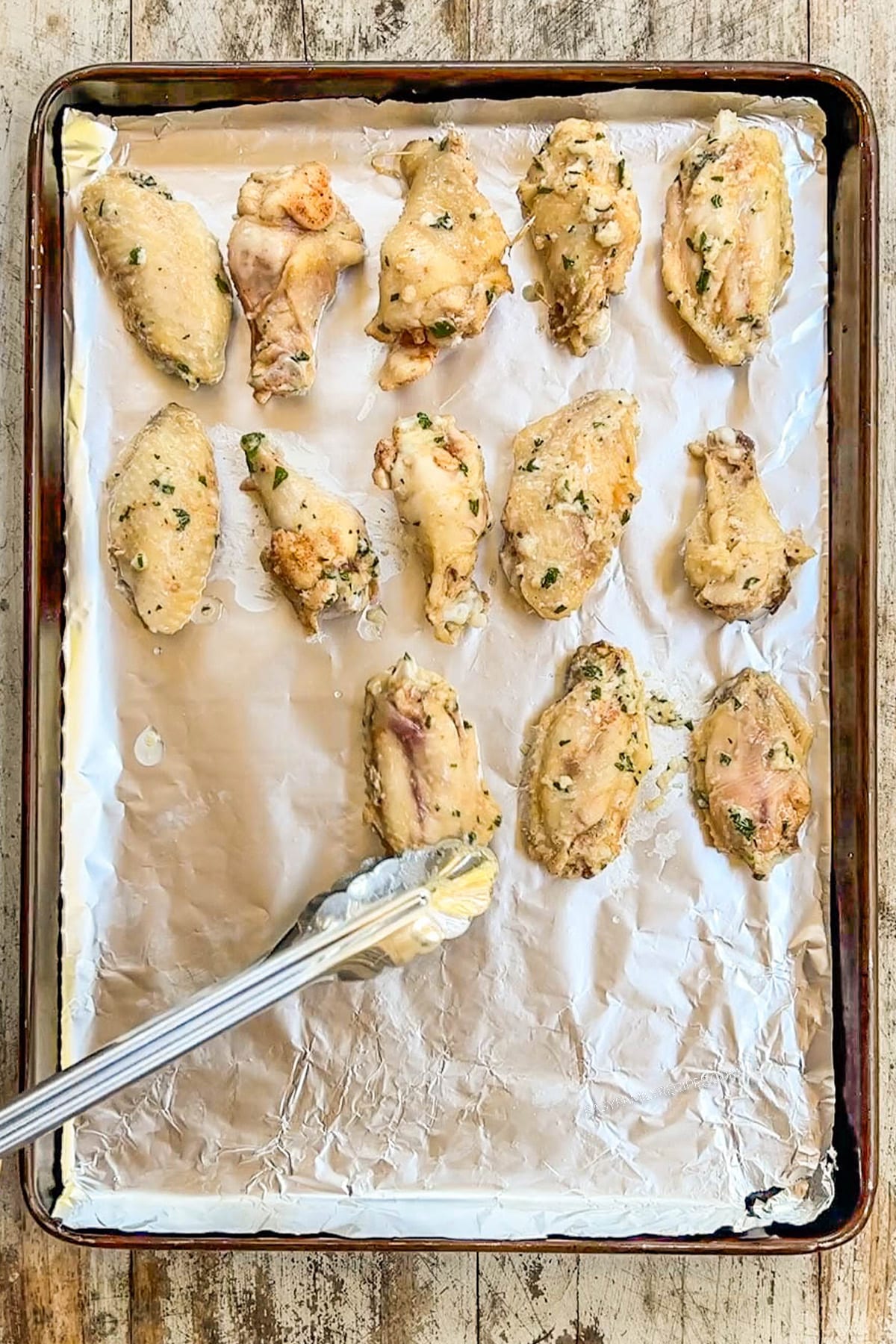 Wings that have been cooked in the Crock Pot are lined up on a baking sheet for a quick crisping before serving.