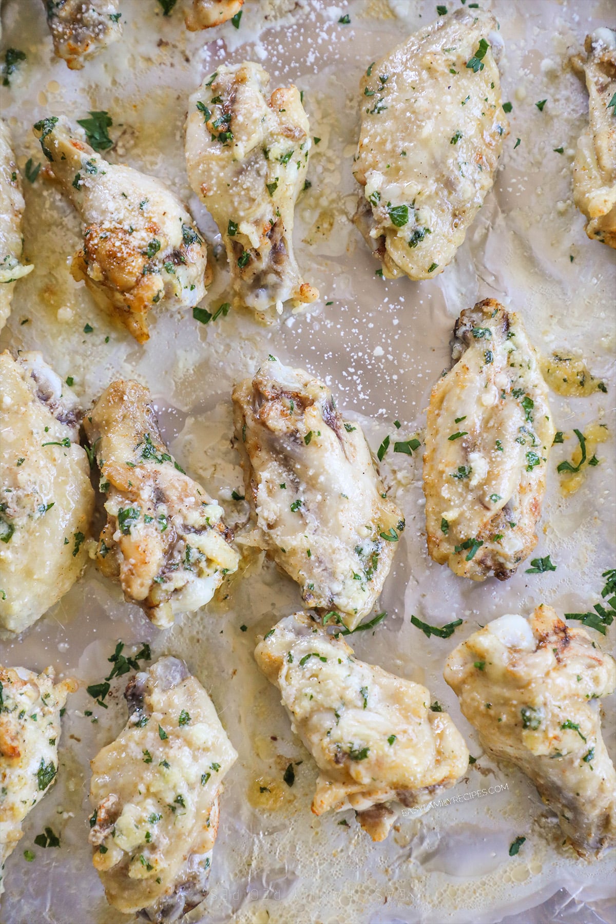 Slow cooker garlic Parmesan wings lined up on a baking sheet, ready to crisp up in the oven.