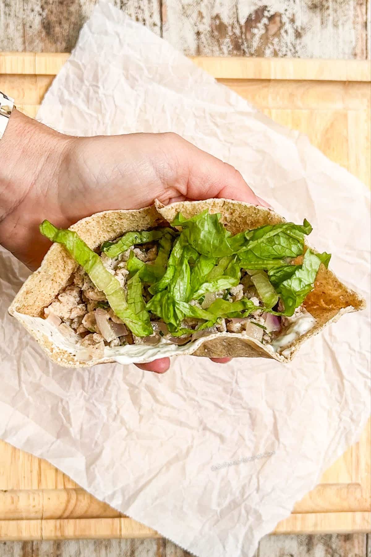 Letta being added on top of ground chicken mixture inside a pita.