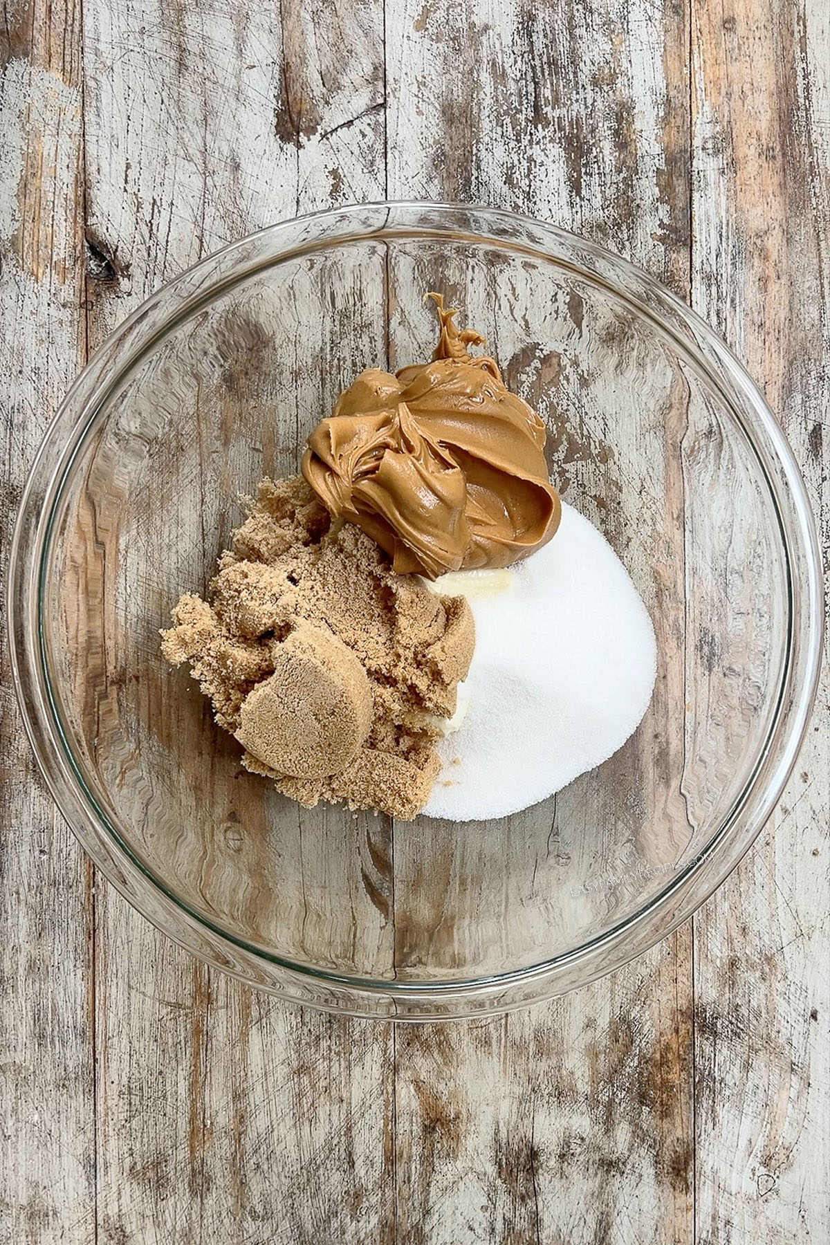 The ingredients for Peanut Butter & Jelly Cookies are added to a glass bowl.