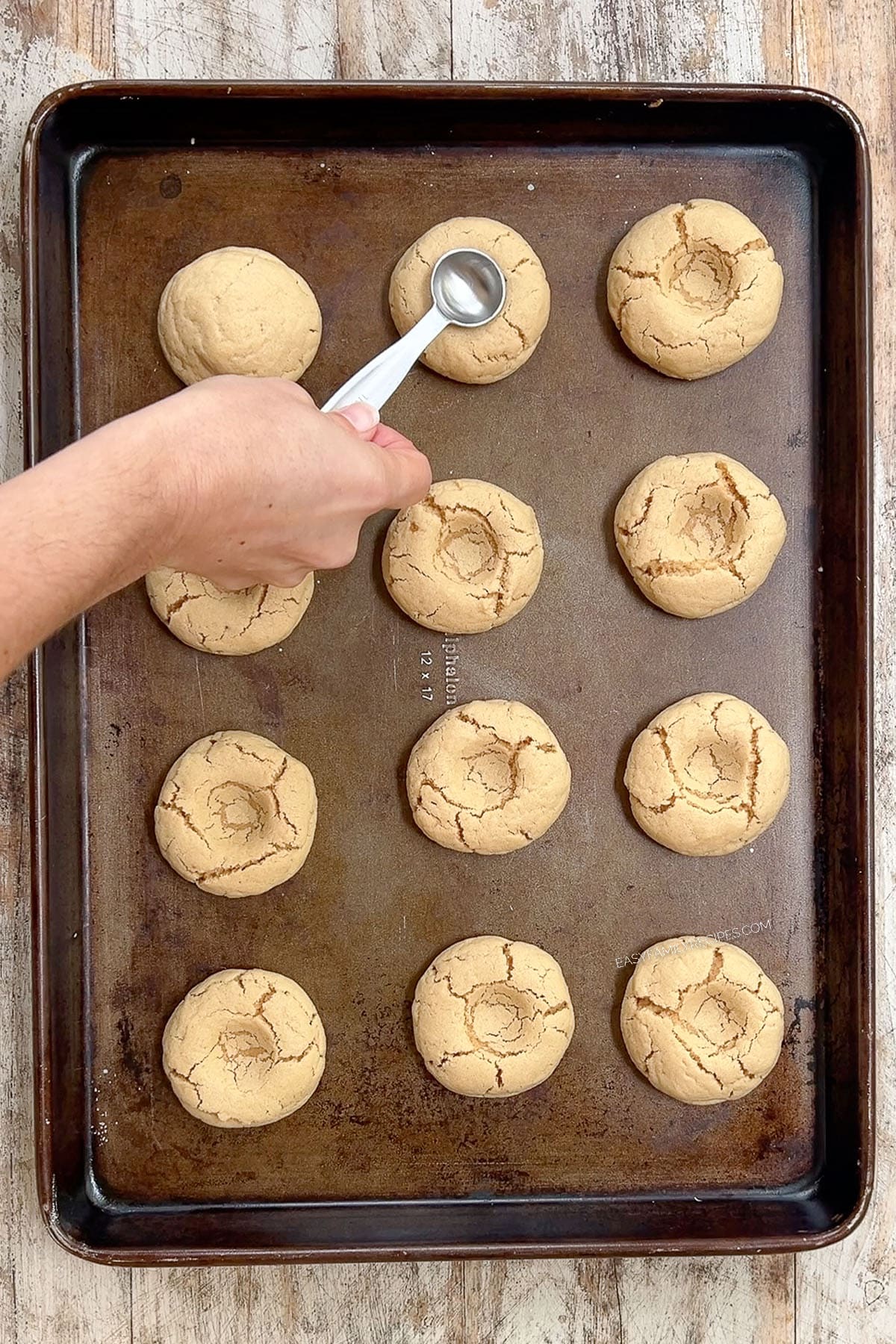 Making the imprint in Peanut Butter & Jelly Cookies on a cookie sheet.