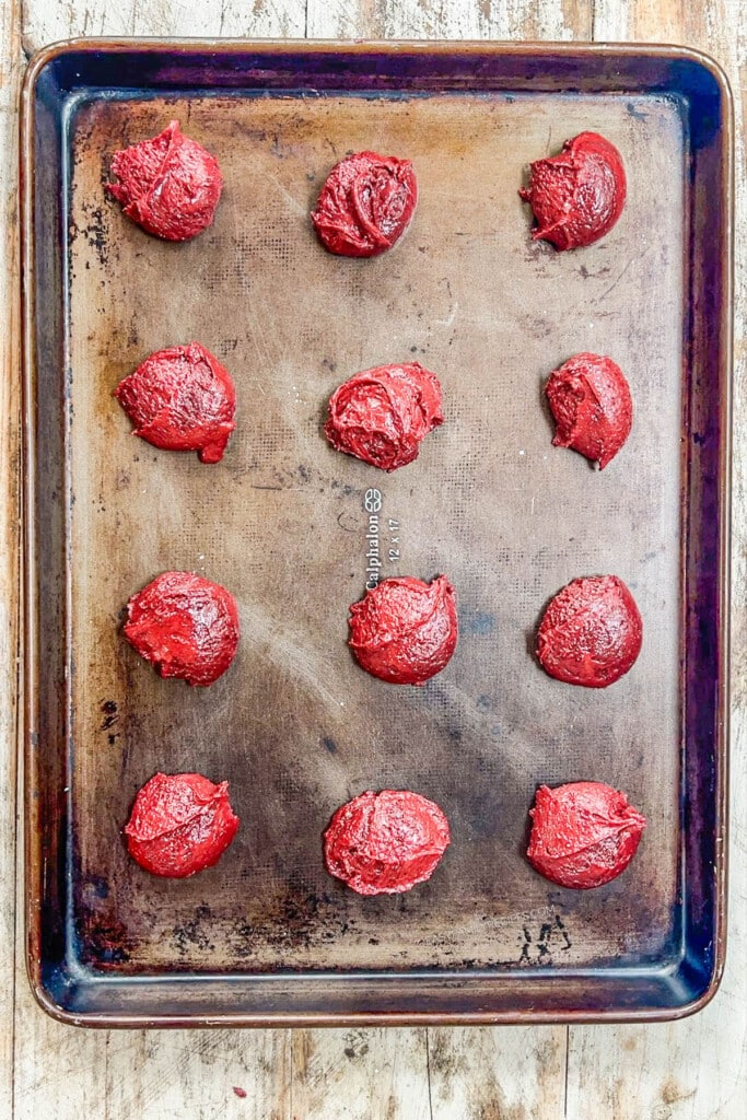 cookie dough balls lined on a baking sheet.