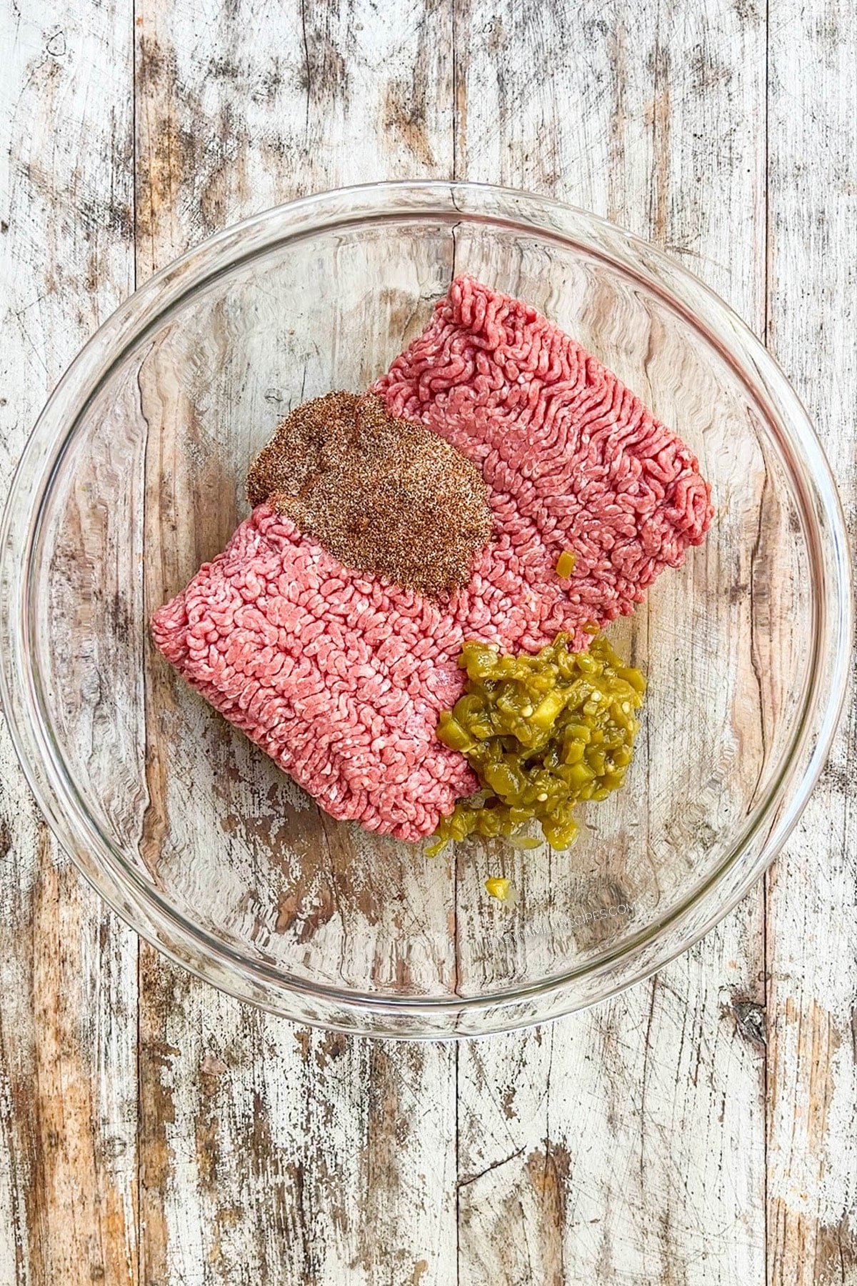 Ground beef and seasonings in a bowl before mixing.