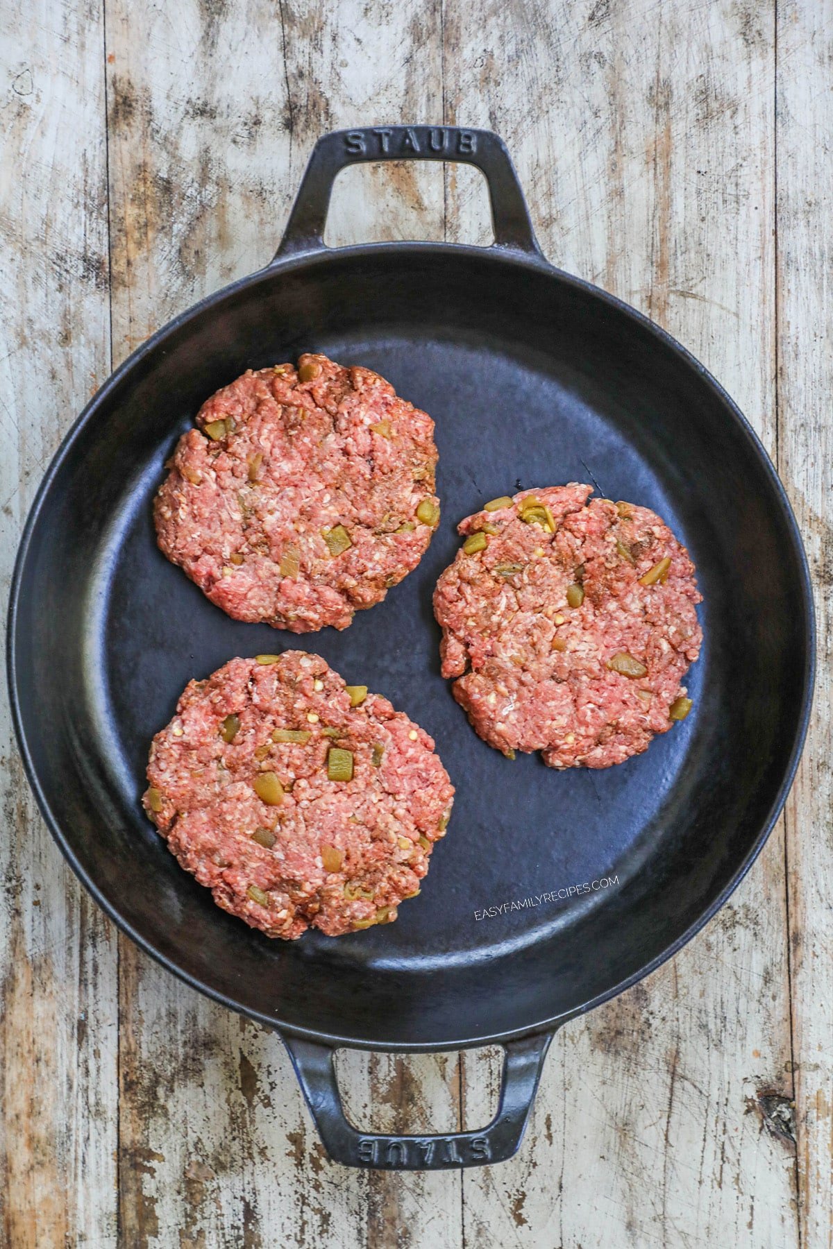 3 burger patties on a skillet.