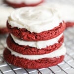 three red velvet cake mix cookies stacked on a cooling rack.