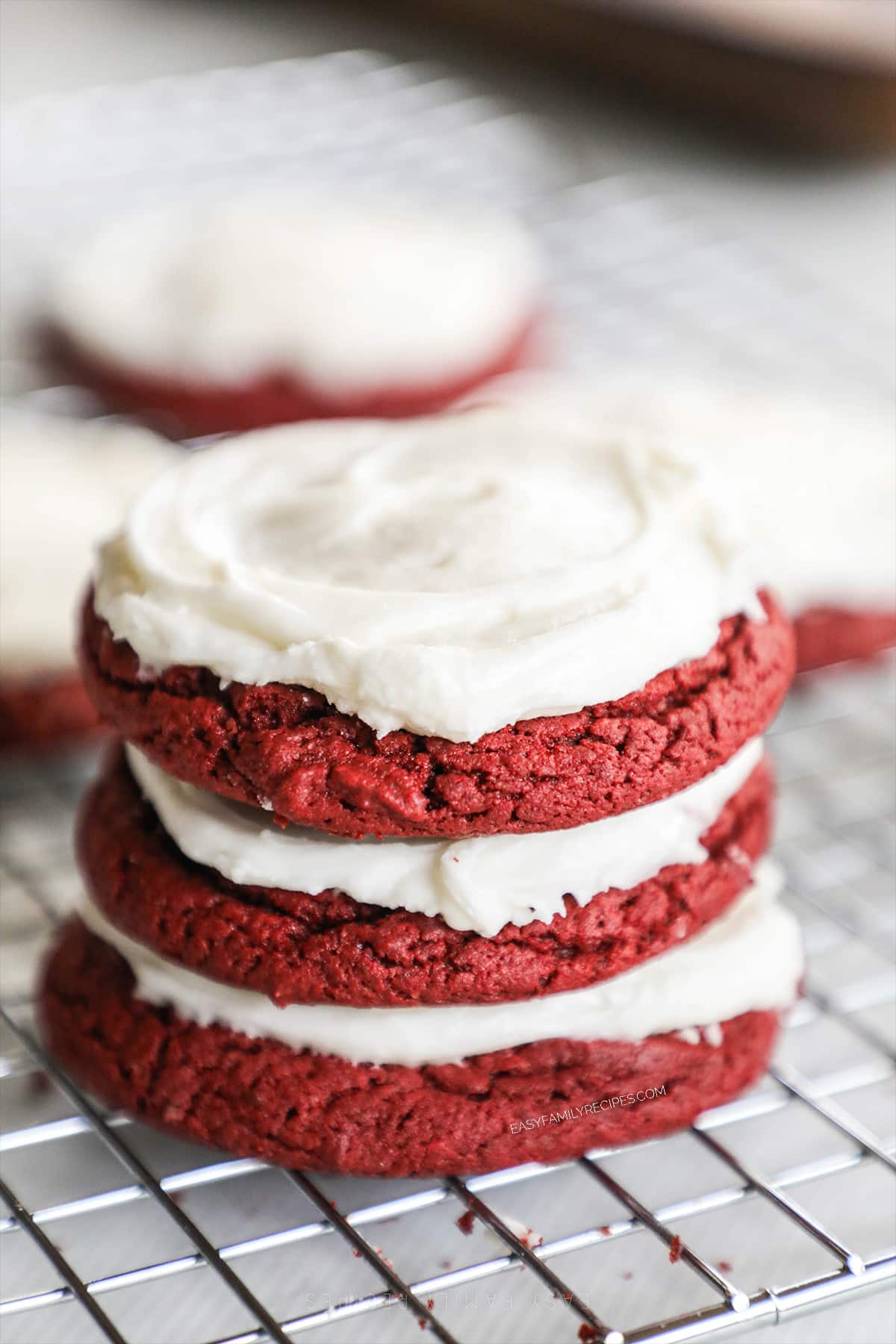 three red velvet cake mix cookies stacked on a cooling rack. 