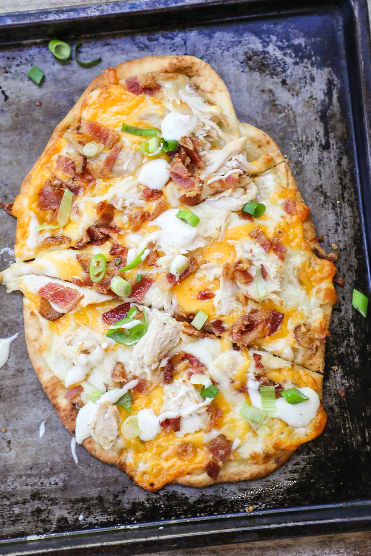 Chicken bacon ranch flatbread pizza on a baking sheet. 