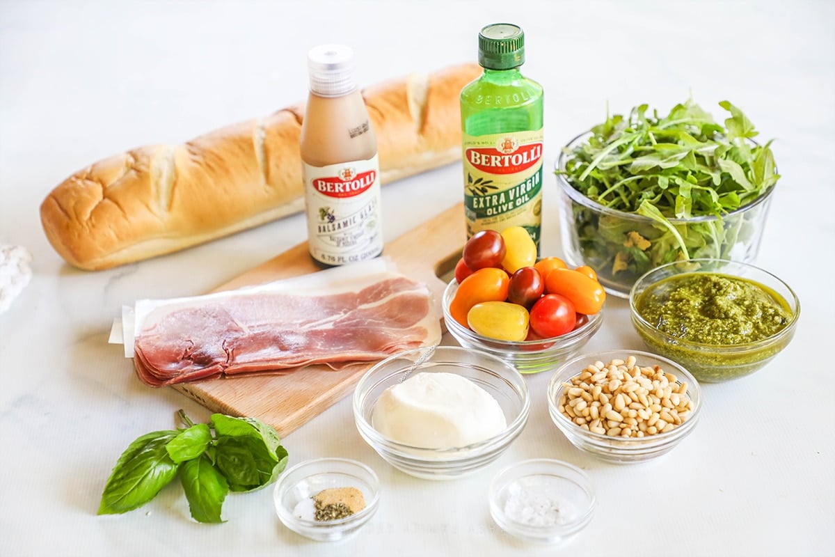 Ingredients for burrata arugula salad on a white background.