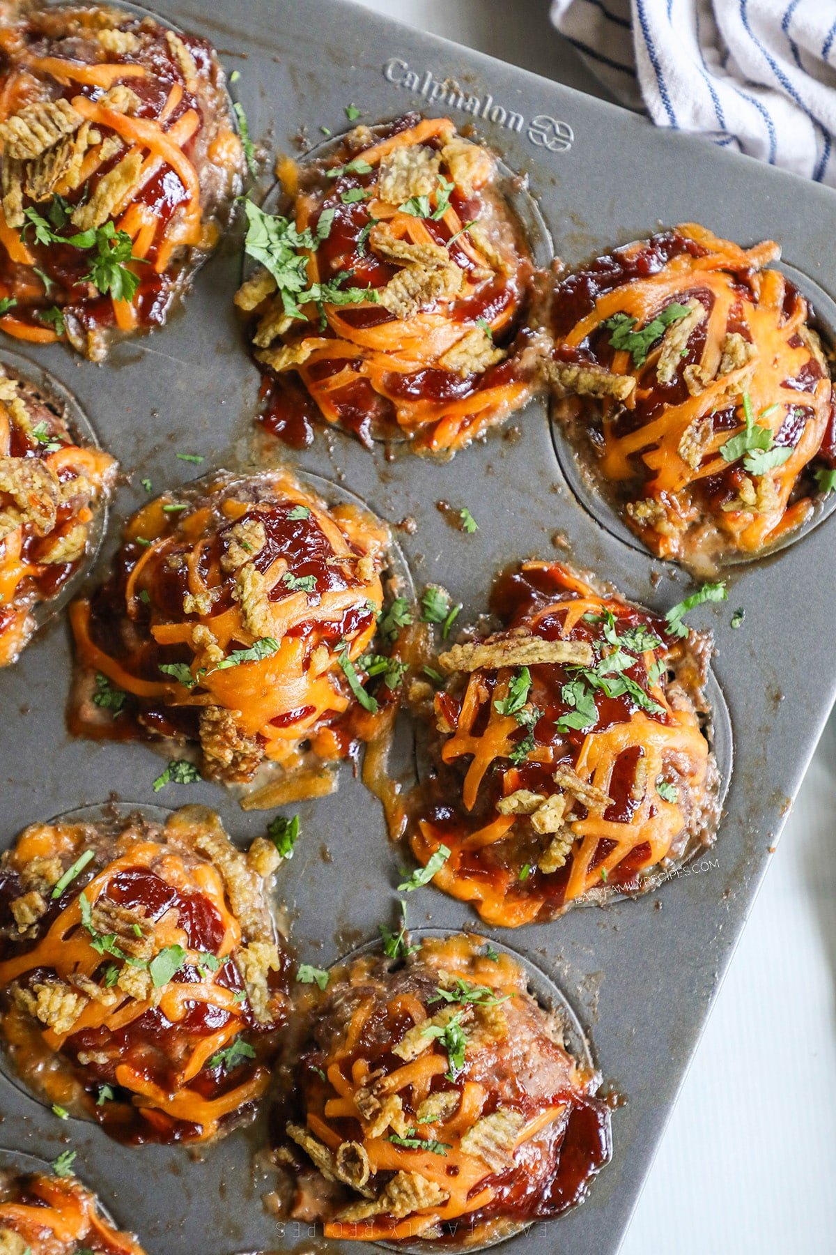 BBQ meatloaf muffins in a muffin pan with melted cheese on top.