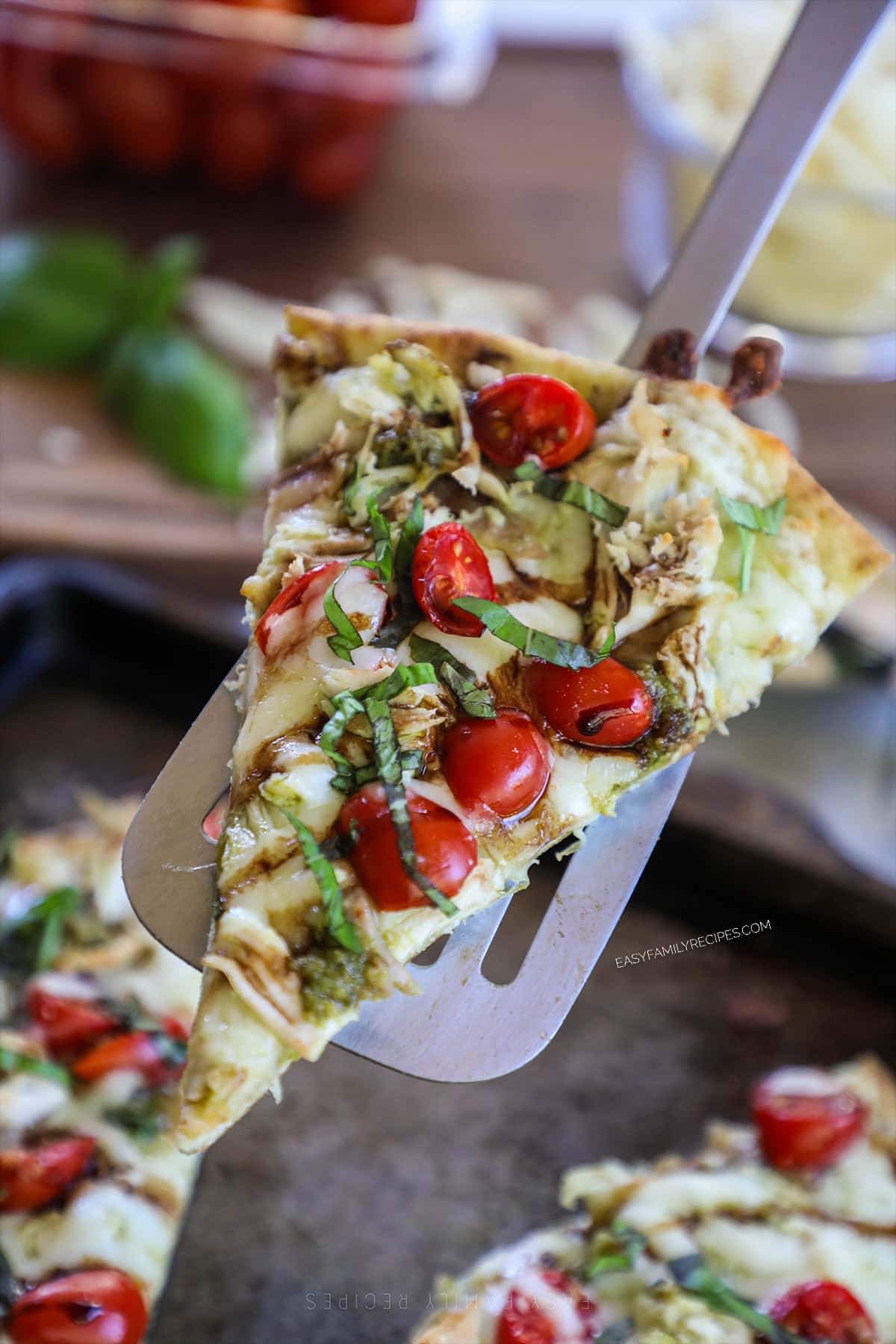 Slice of a caprese chicken flatbread pizza being lifted up for serving.