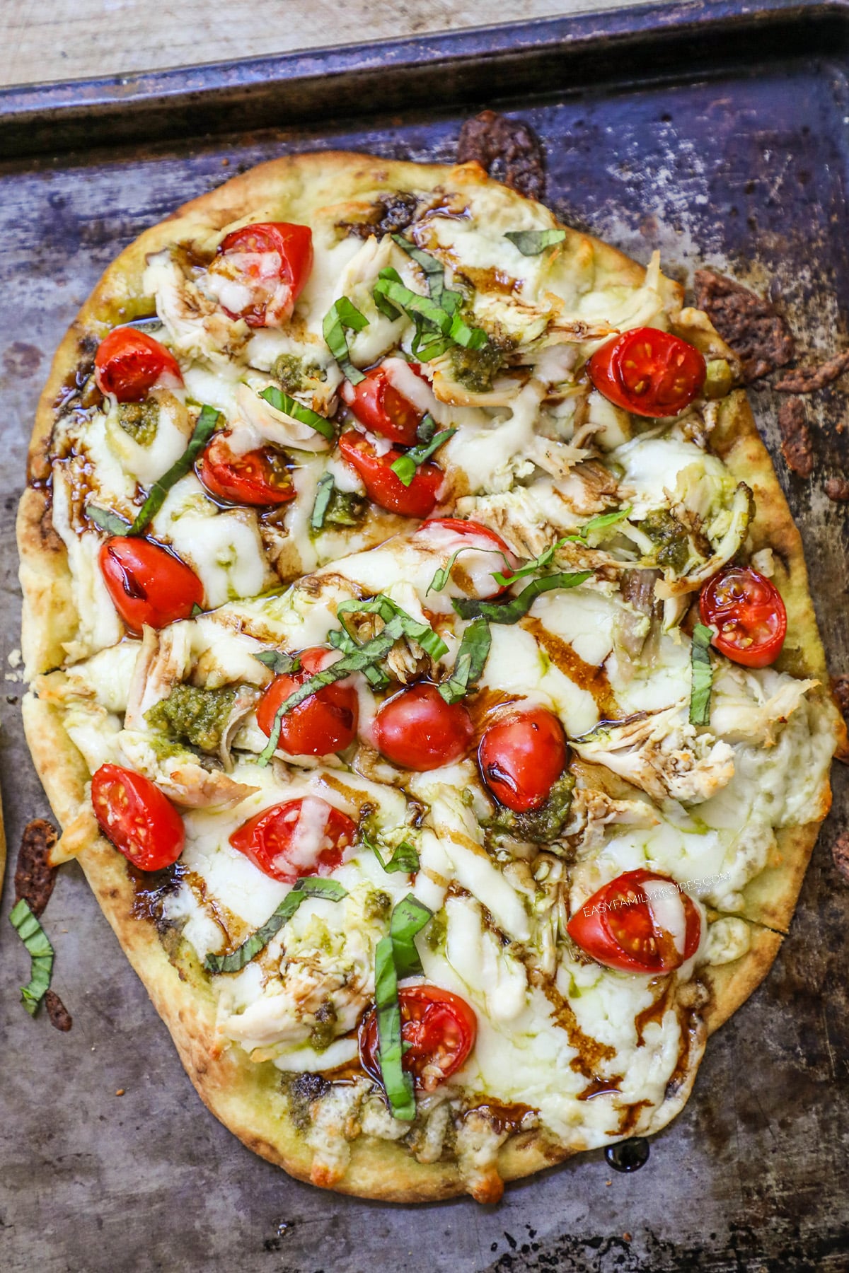 Caprese chicken flatbread with pesto and a drizzle of balsamic glaze.