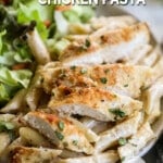 Garlic Parmesan Chicken Pasta served on a white plate with a green salad on the side. The text reads, "Garlic Parmesan Chicken Pasta."