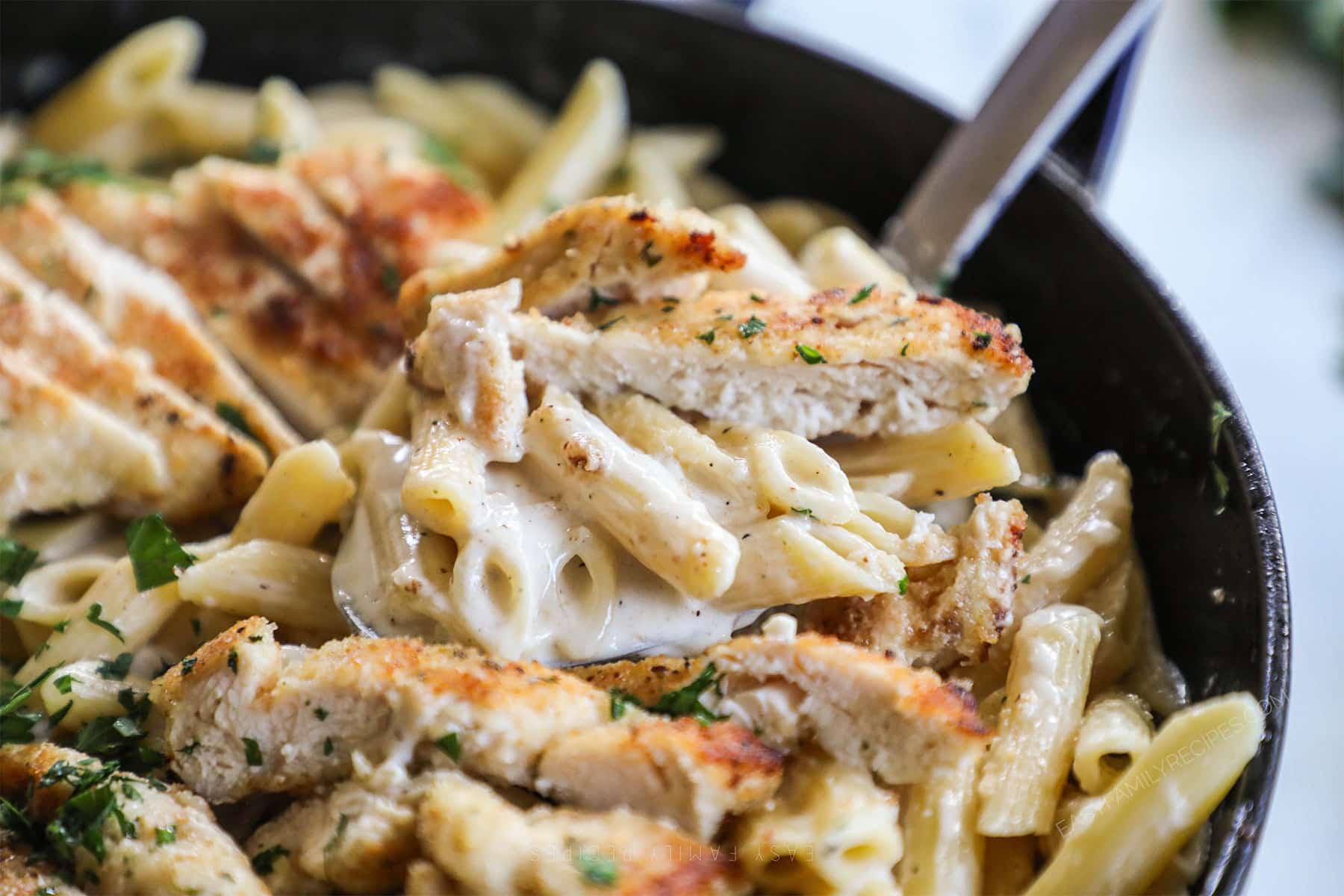 Close up of Garlic Parmesan Chicken Pasta being lifted from the dish and served for an easy dinner.