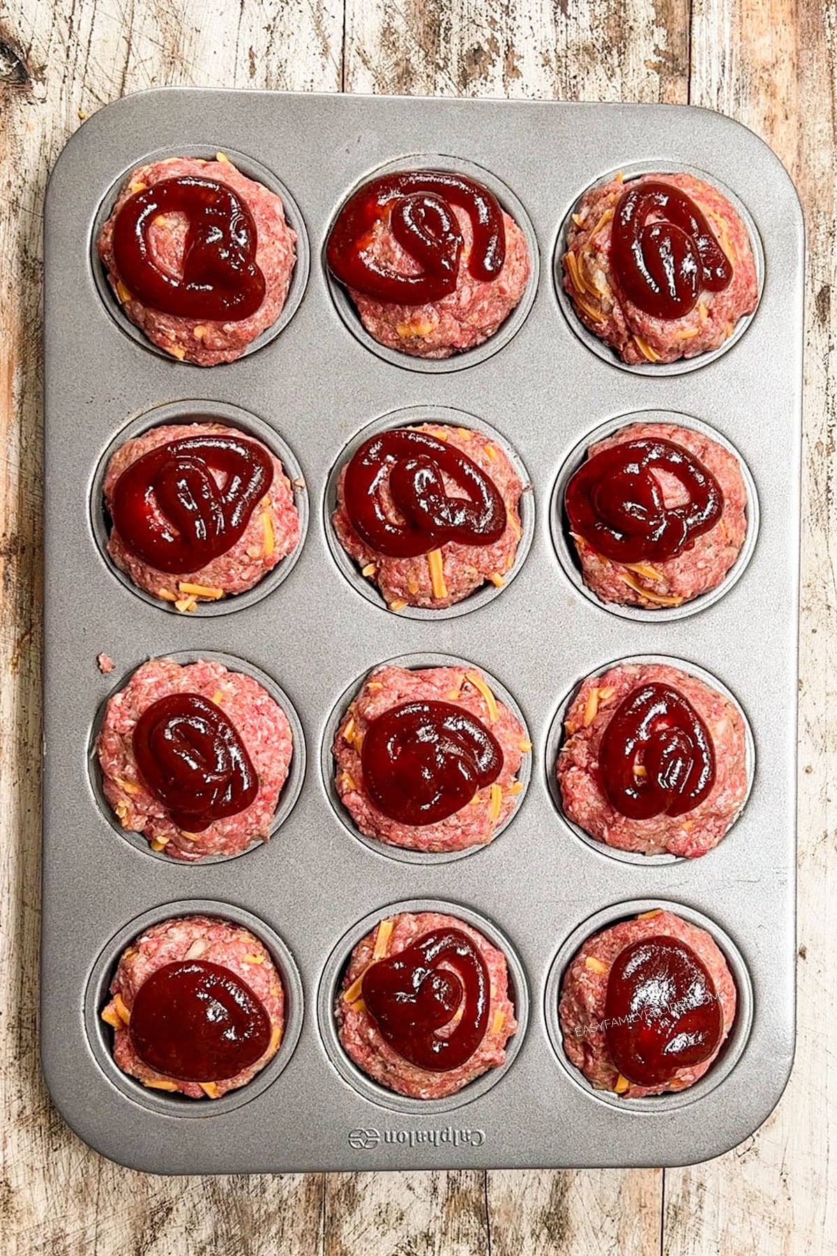 Bbq sauce added on top of meat balls in a muffin pan.