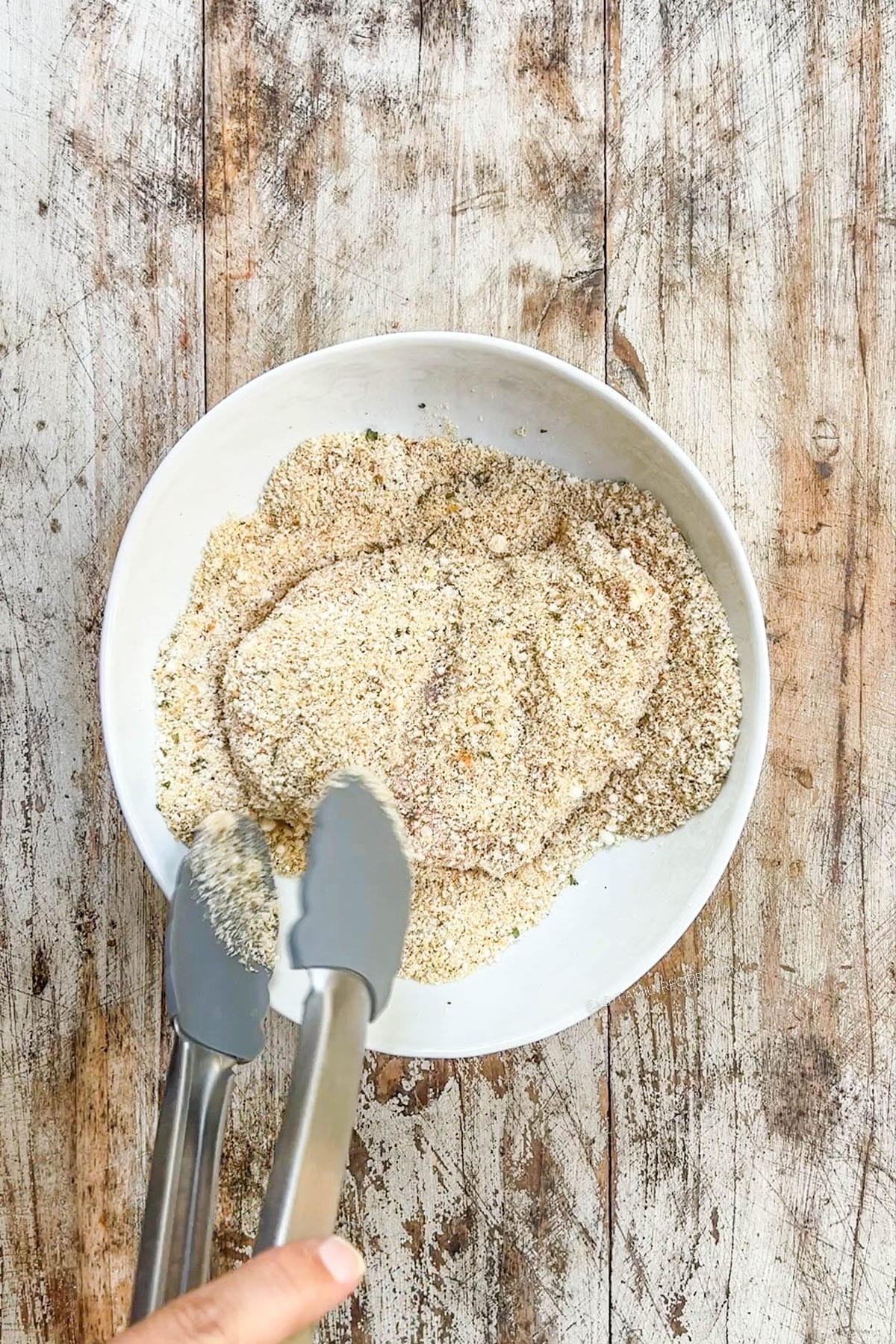 A top view of chicken being dredged in garlic Parmesan bread crumbs for Garlic Parmesan Chicken Pasta.