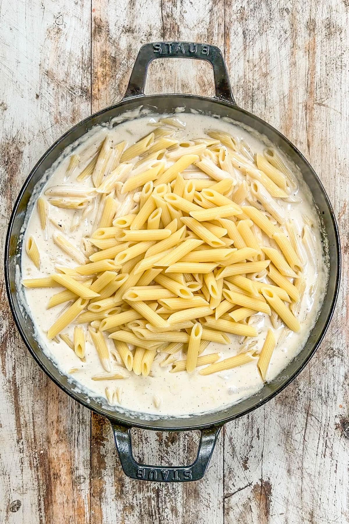 A top view of Garlic Parmesan Chicken Pasta in process. The pasta is mixed into the creamy sauce.