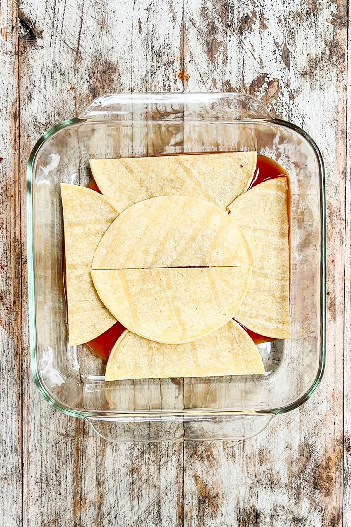 Step 2 of how to make Southwest Chicken Casserole. Corn tortillas are layered on the bottom of the dish.