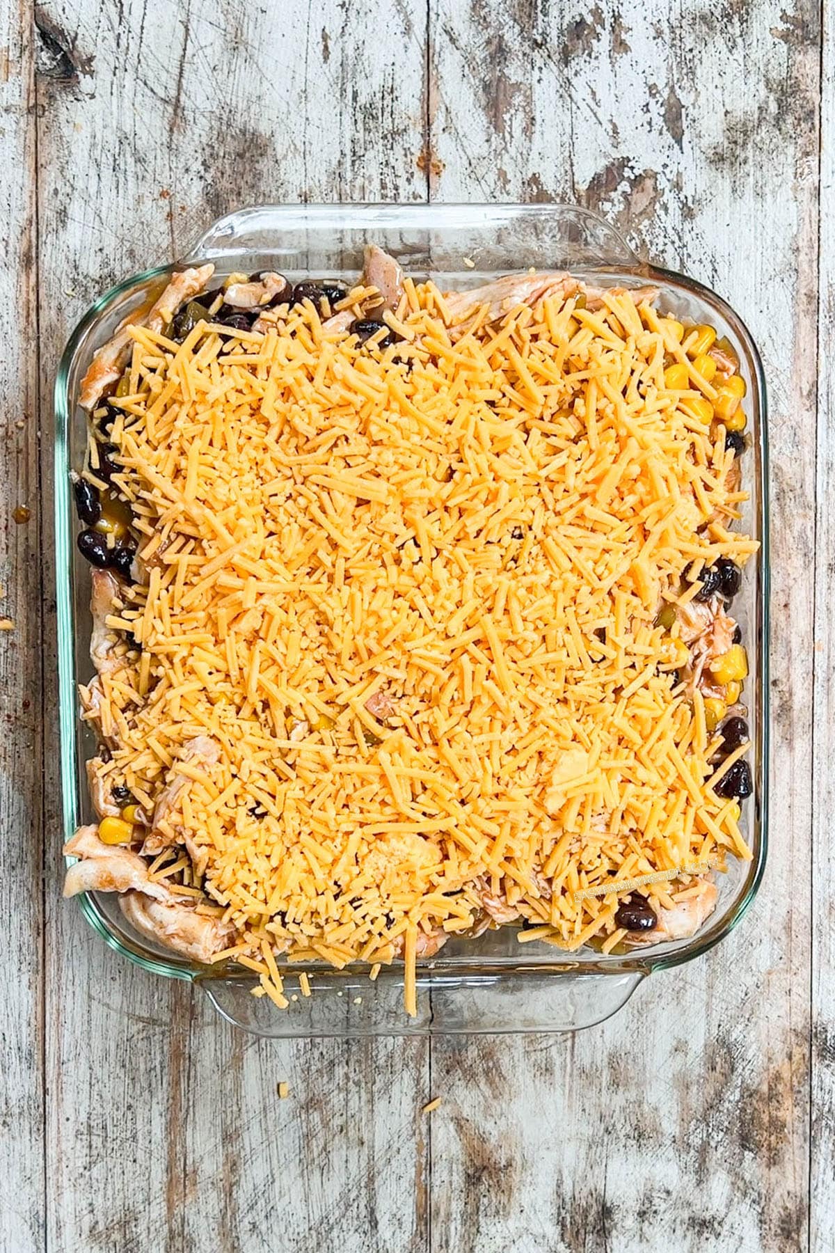 Step 5 of how to make Southwest Chicken Casserole. Shredded cheese is sprinkled over the top.