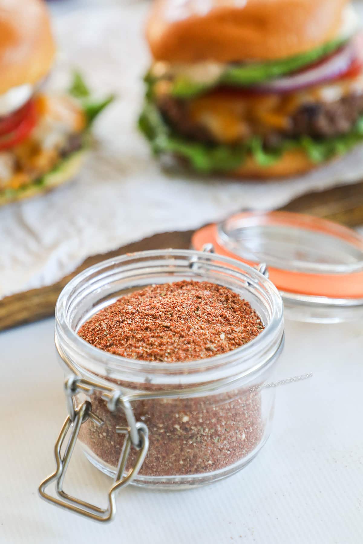 Open jar full of southwest seasoning mix with a burger in the background.