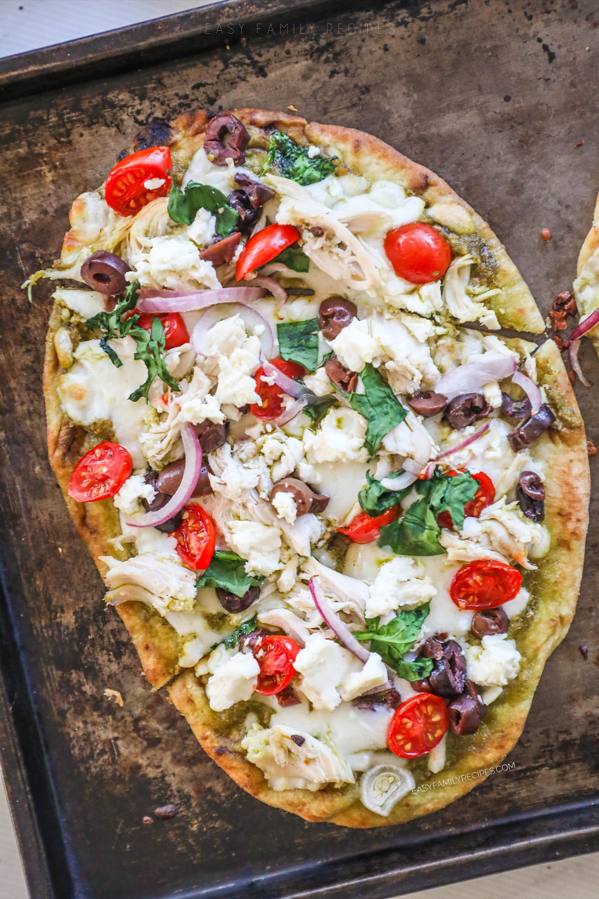 A top view of Mediterranean Flatbread on a baking sheet, cut into slices and ready to serve. 