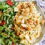 A serving of Chicken Noodle Casserole on a white plate with a salad served alongside. The text reads, "Chicken Noodle Casserole."