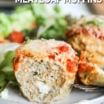 A side view of Chicken Parmesan Meatloaf Muffins on a white plate with a green salad. The text reads, "Chicken Parmesan Meatloaf Muffins."