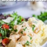 a pile of crockpot creamy garlic chicken on a plate with a side salad.