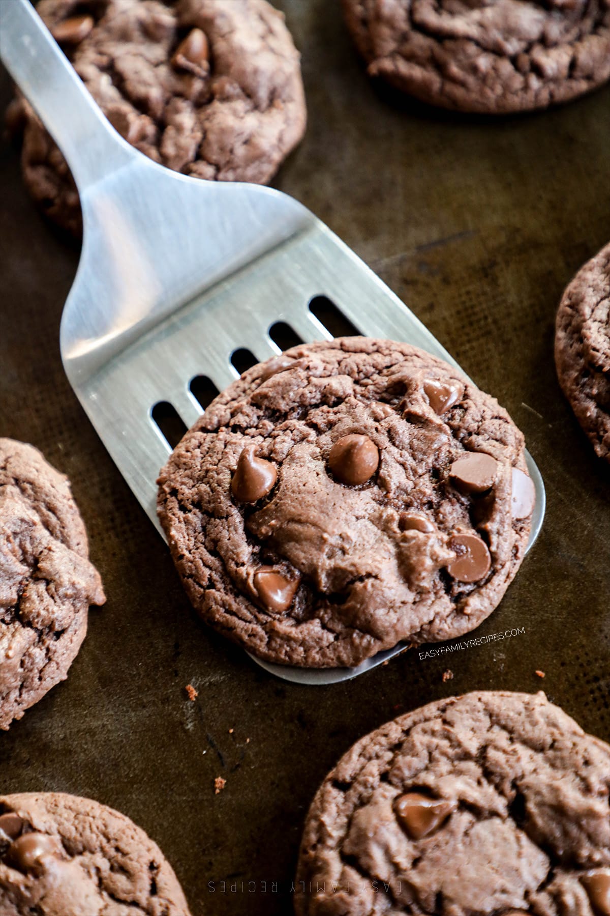 A Devil's Food Cookie is lifted off a cookie sheet by a spatula.