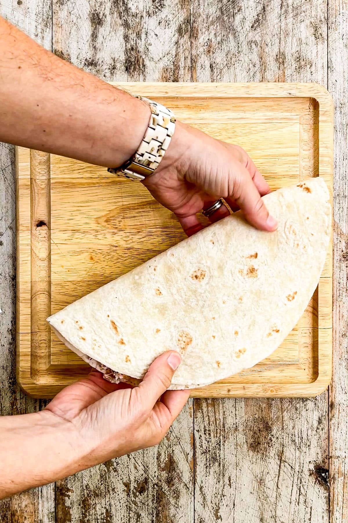 An action image showing a flour tortilla being folded over the filling for Chicken Bacon Ranch Quesadillas.