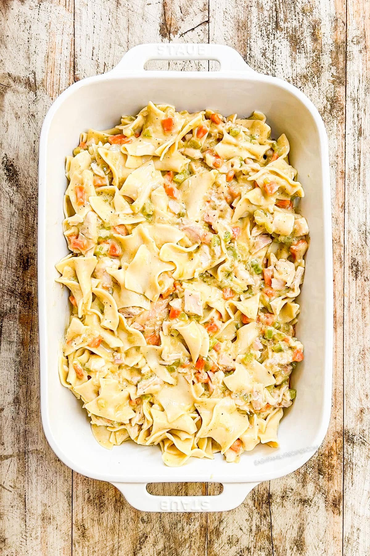 A top view of the filling for Chicken Noodle Casserole in a white baking pan.